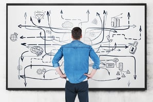 A man staring at a complex diagram on a whiteboard