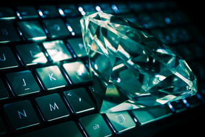 A cut diamond resting on a laptop keyboard