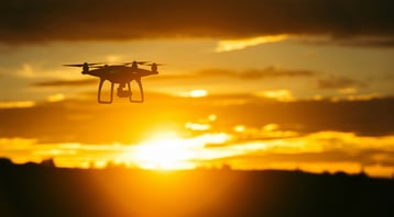 A pipeline inspection drone flying in front of a blazing sunset